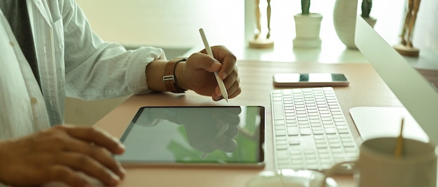 Side view of male office worker using digital tablet on office desk