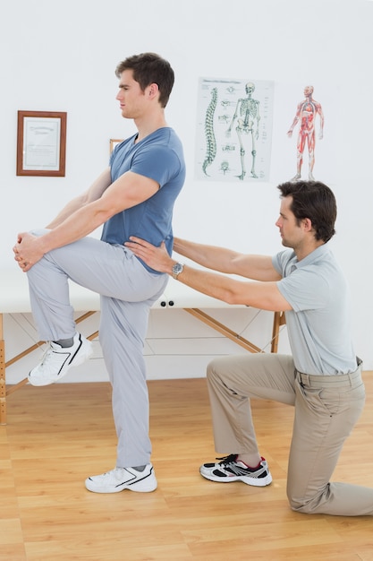 Side view of a male physiotherapist examining mans back