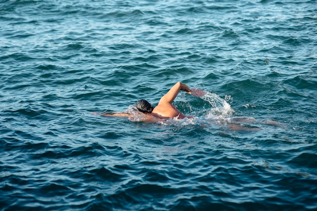 Foto vista laterale del nuotatore maschio che nuota in acqua