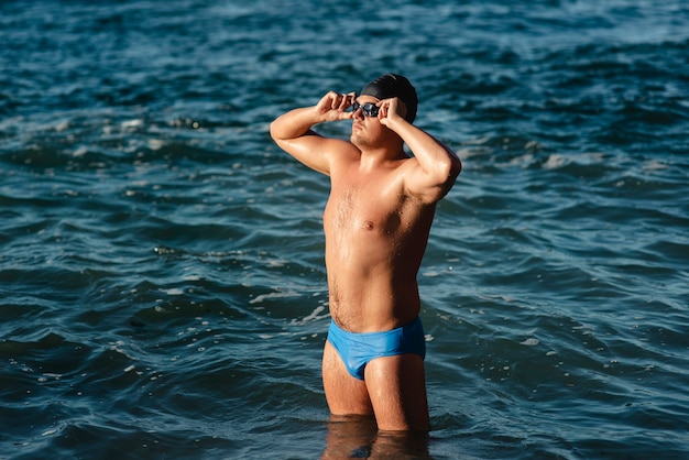 Foto vista laterale del nuotatore maschio con occhiali da nuoto e cappuccio