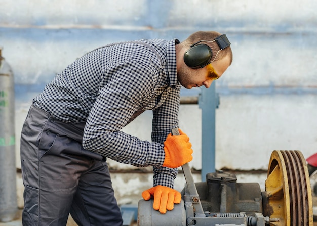 Side view of male worker with headphones and protective glasses