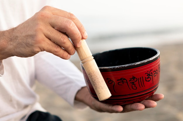 Side view of man on the beach holding yoga bowl