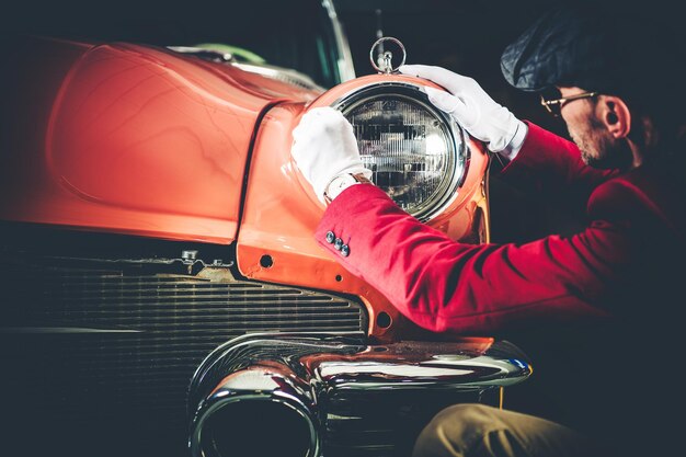 Foto vista laterale di un uomo che controlla il proiettore di un'auto d'epoca