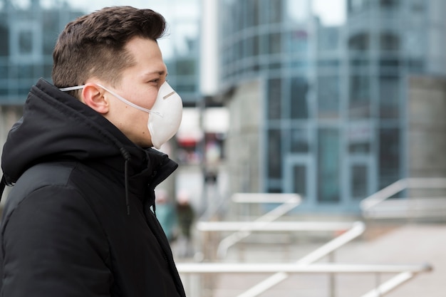 Vista laterale dell'uomo in città con maschera medica e copia spazio