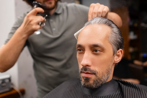 Foto uomo di vista laterale che ottiene un taglio di capelli