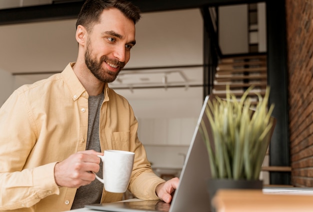 Side view man having video call on laptop