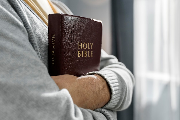 Photo side view of man holding bible in arms