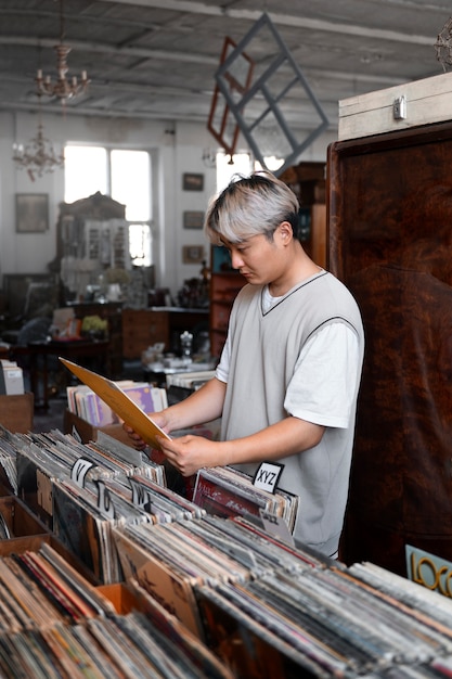 Foto uomo di vista laterale che tiene disco in vinile