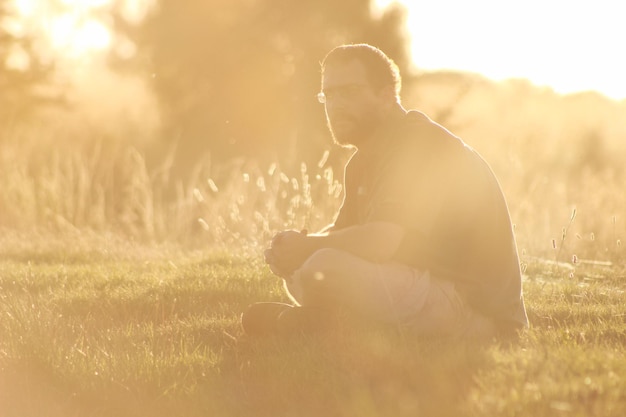 Photo side view of man looking away while sitting on grass