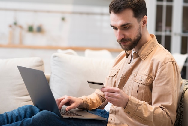 Photo side view of man looking at credit card for online shopping