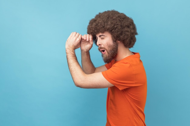 Side view of man making glasses shape looking through monocular gesture with amazed expression