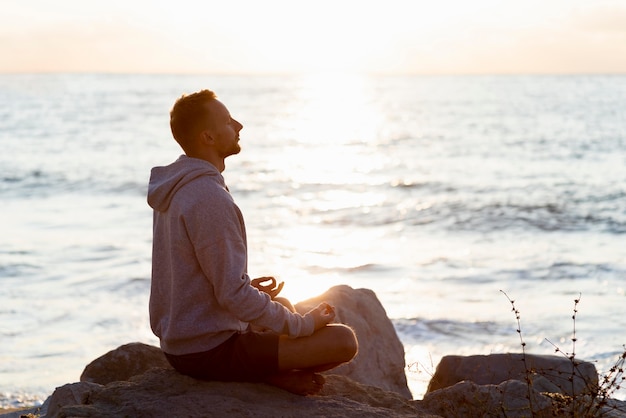 Photo side view man meditating on the beach