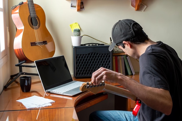 Photo side view of man playing guitar while sitting at home