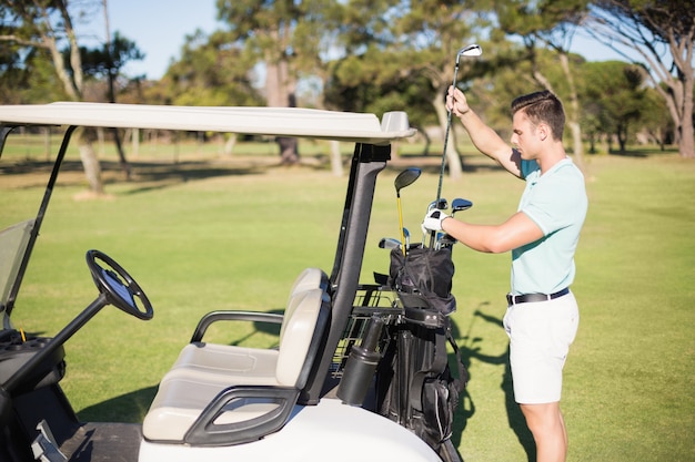 Side view of man putting golf club in bag