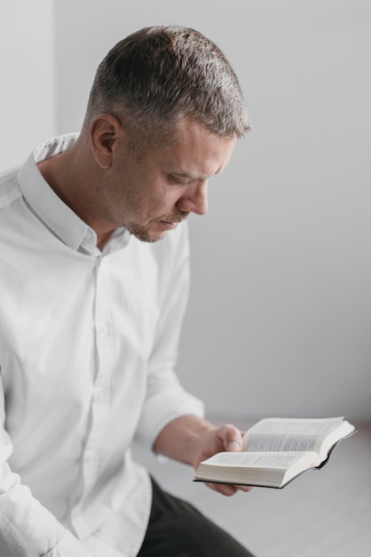 Foto uomo di vista laterale che legge un libro sacro