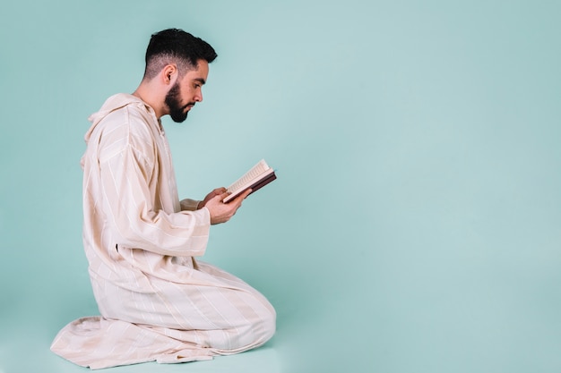 Side view of man reading in quran