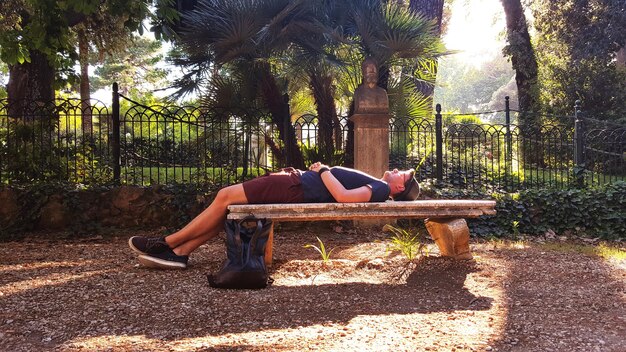 Foto vista laterale di un uomo che si rilassa su una panchina al parco