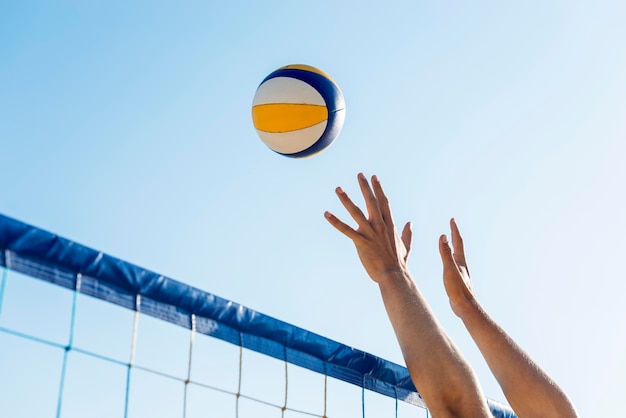 Foto vista laterale delle mani dell'uomo che si preparano a colpire la pallavolo in arrivo sopra la rete