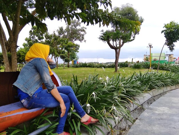 Side view of man sitting on field against sky