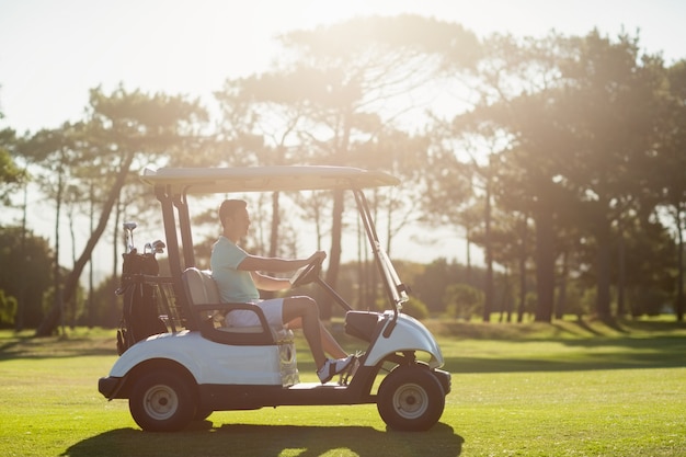 Side view of man sitting in golf buggy