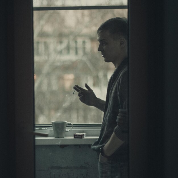 Side view of man smoking at window