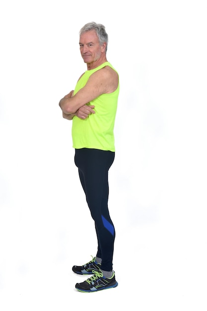 Side view of a man in sportswear tights and fluorescent yellow sleeveless and looking at camera and arms crossed on white background