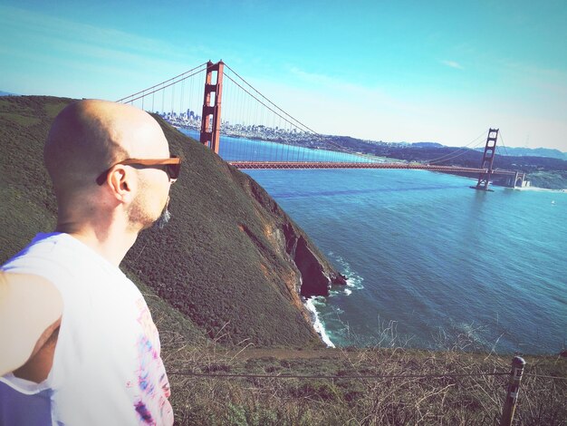 Side view of man standing against golden gate bridge