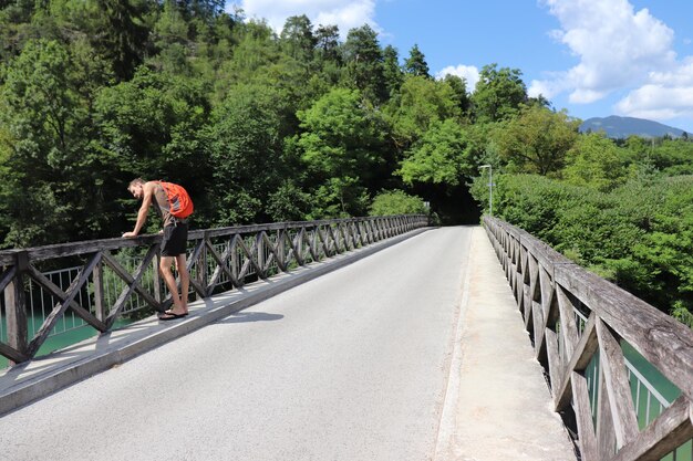 Foto vista laterale di un uomo in piedi su un ponte nella foresta