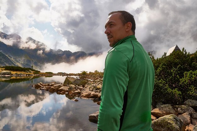 Foto vista laterale di un uomo in piedi vicino al lago contro un cielo nuvoloso