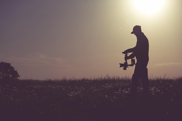 Side view of man standing on field against sky during sunset