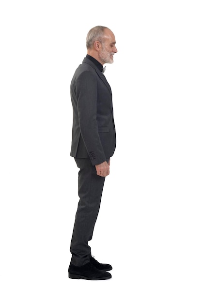 Side view of a man standing with suit and bow tie on white background