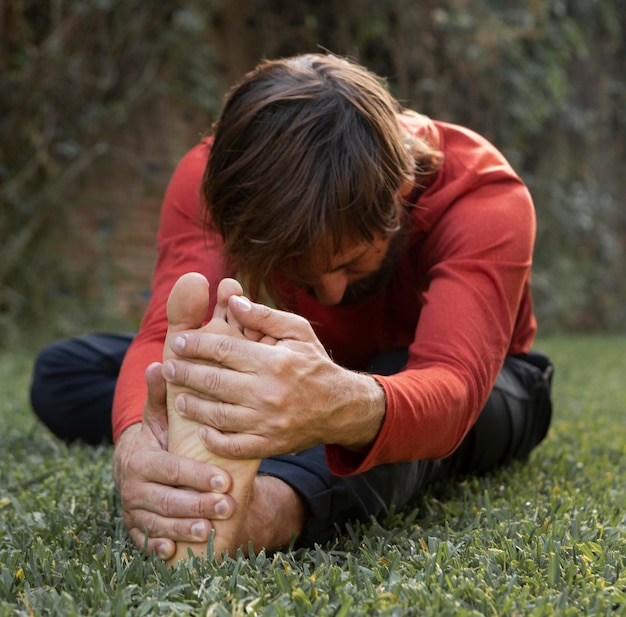 side view of man stretching on the grass outdoors while doing yoga