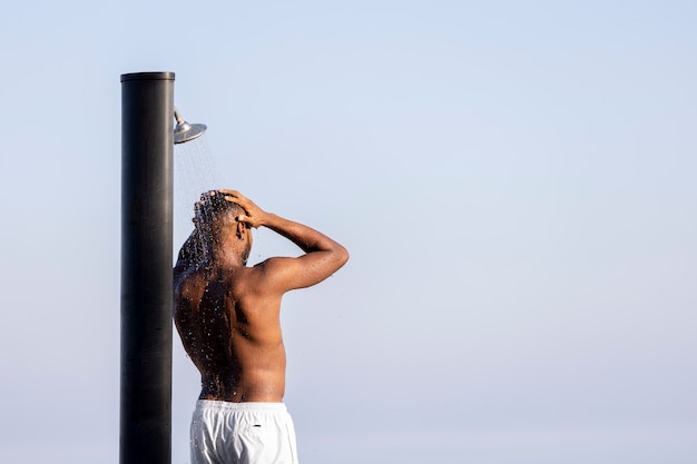 side view man taking shower outside