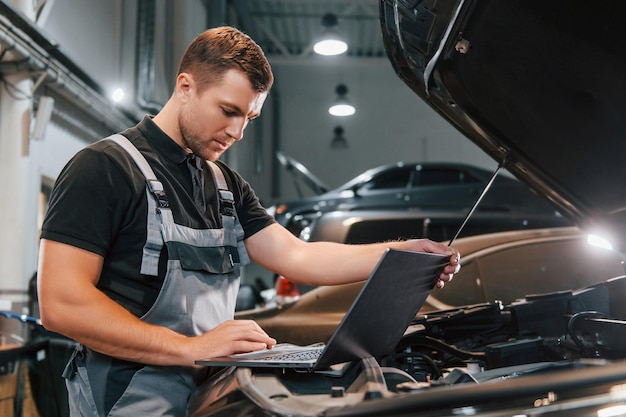 Side view Man in uniform is working in the auto service