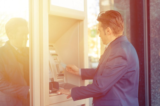 side view of man using atm machine