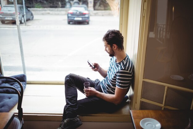 Vista laterale dell'uomo che per mezzo del cellulare al caffè