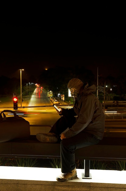 Foto vista laterale di un uomo che usa il cellulare in città di notte