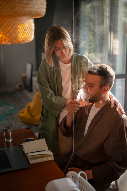 Photo side view man using a nebulizer