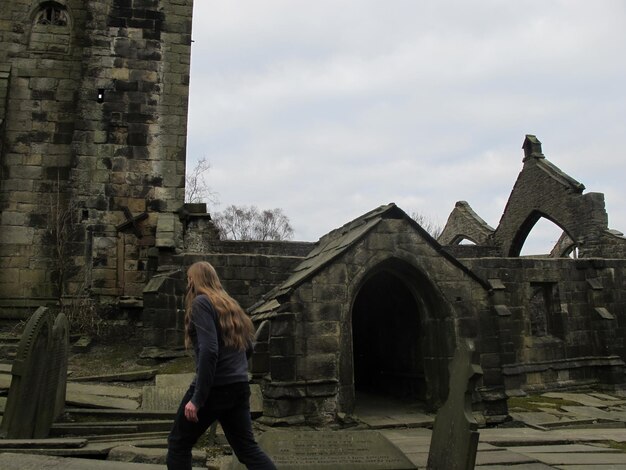 Photo side view of man walking against old church