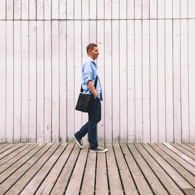 Photo side view of man walking against wall