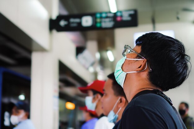 Side view of a man wearing glasses waiting for the train to arrive at the station