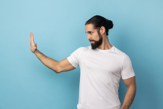 Side view of man wearing white Tshirt showing stop gesture with palm of hand rejecting stress