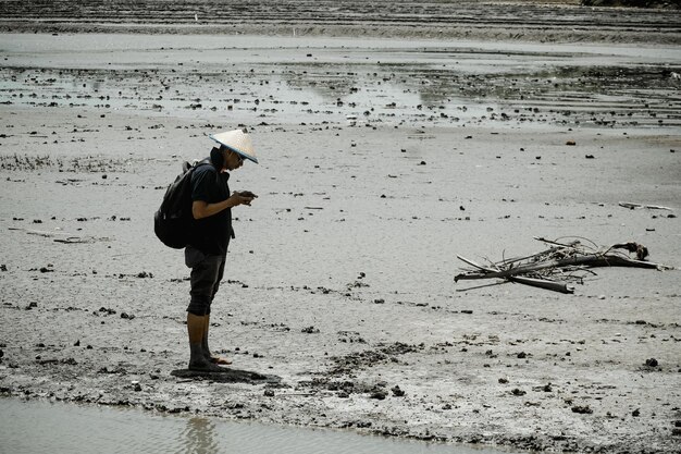 Photo side view of man with backpack standing at beach during sunny day