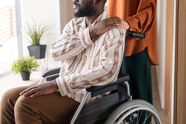 Side view of man with disability keeping his hand on that of female caregiver