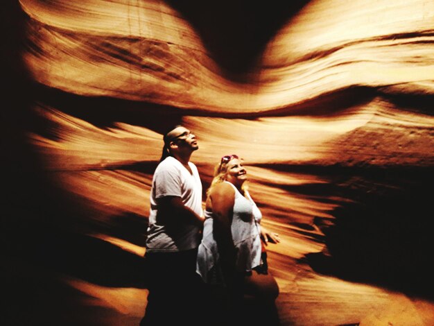 Photo side view of man and woman walking by rock formations