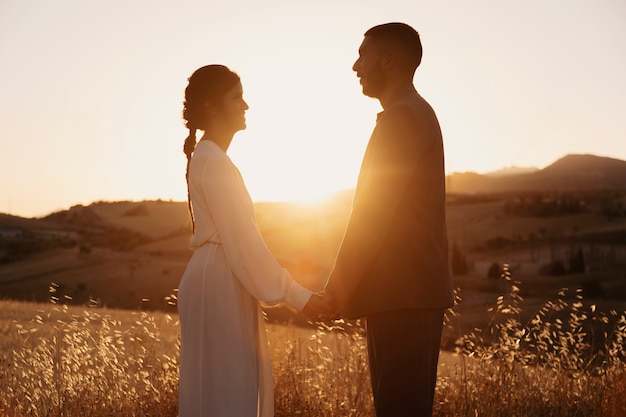 Photo side view married couple holding hands