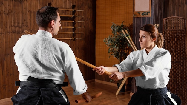 Side view of martial arts instructor training in the practice\
hall with female trainee