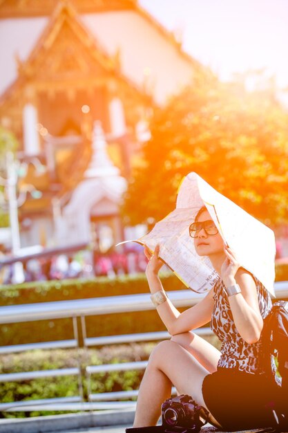 Photo side view of mature woman with paper sitting on footpath in park