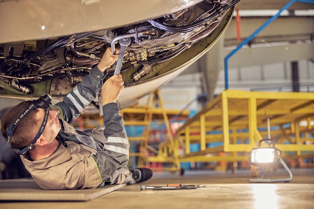 Vista laterale del meccanico che ripara la manutenzione di un grande motore di un aereo passeggeri in un hangar