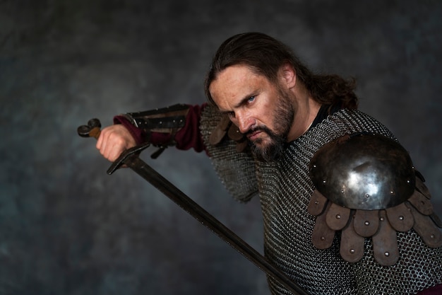 Photo side view medieval soldier posing in studio